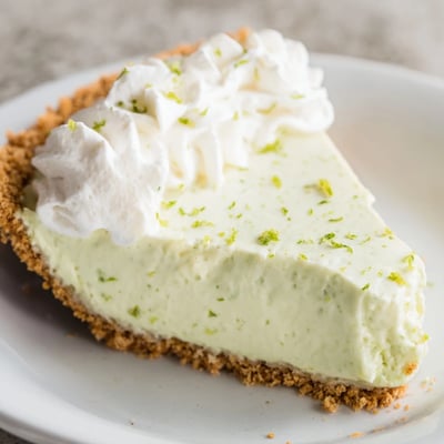 Key Lime Pie with Whipped Cream Topping showcases a creamy, tangy green filling inside a golden graham cracker crust.